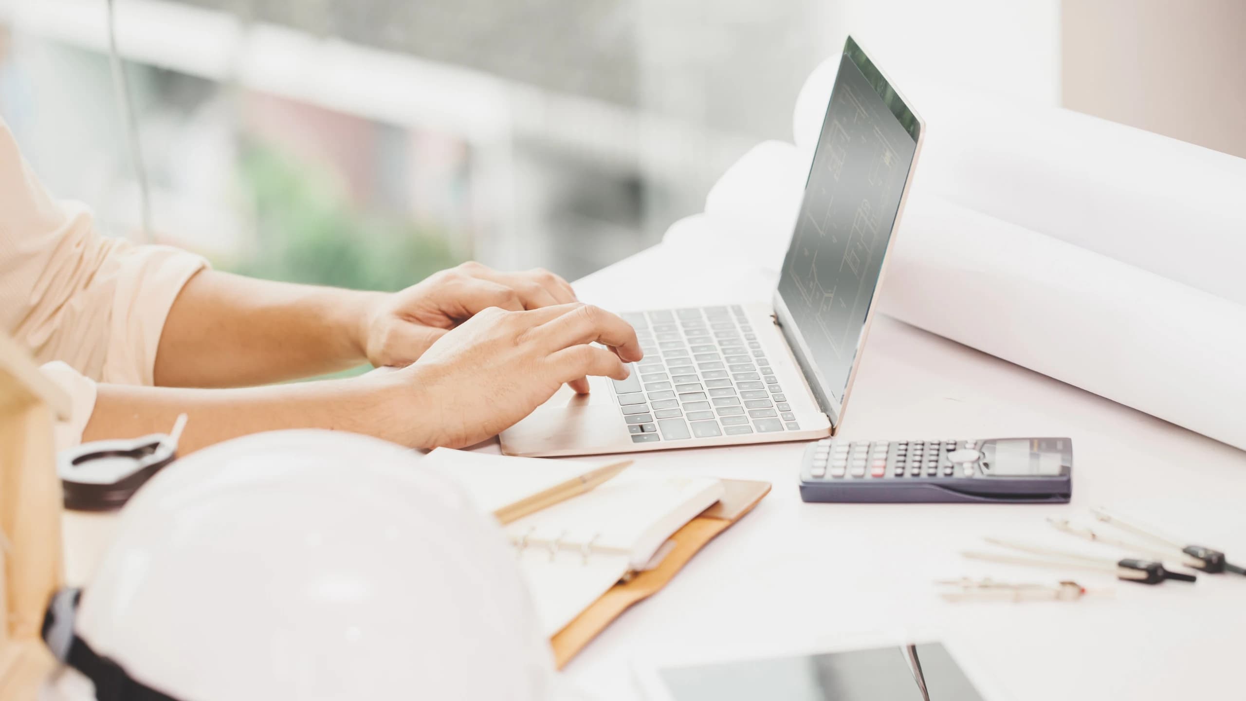 Mesa con planos, calculadora y documentos para tomar decisiones inmobiliarias